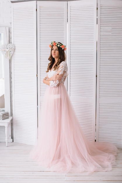 Mujer en bata rosa posando en estudio blanco