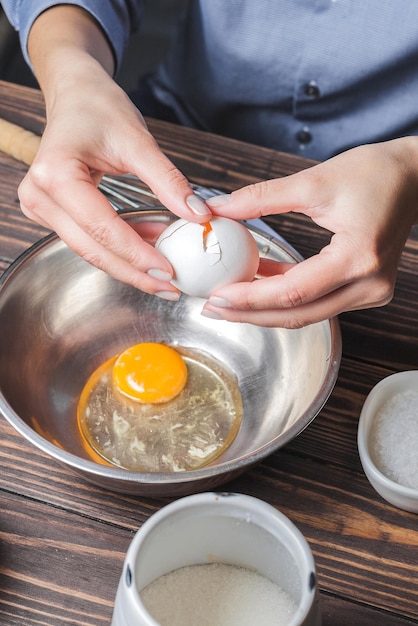 Foto mujer bate huevos para hacer masa en un recipiente de metal preparación de masa para hornear panqueques enfoque selectivo