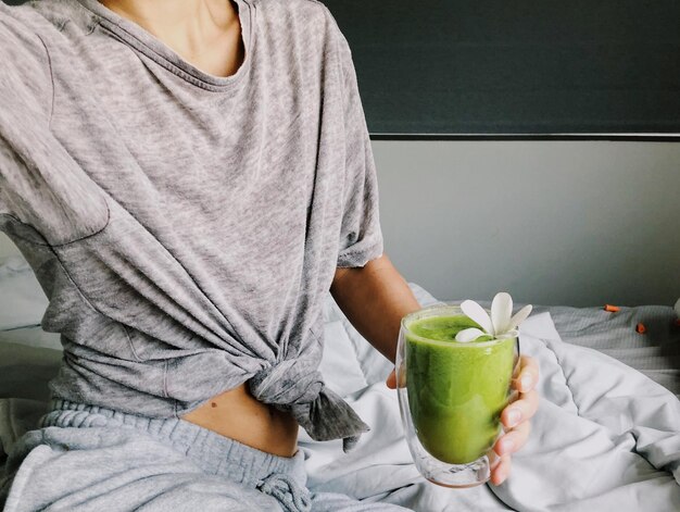 Mujer con un batido verde por la mañana