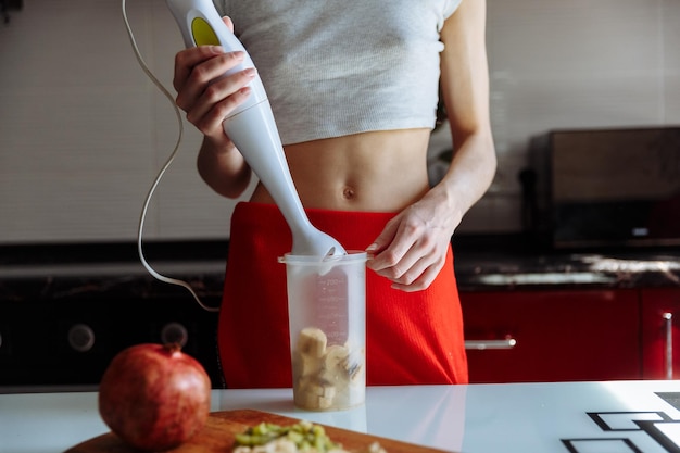 Mujer con batidora de mano haciendo polvo de proteína de plátano dulce batido batido de proteína después del entrenamiento dieta de nutrición deportiva después del gimnasio Estilo de vida saludable