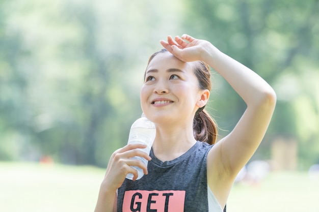 Mujer bebe agua mientras hace yoga en el parque