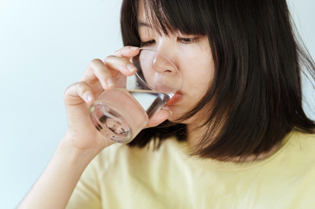 Una mujer bebe agua de un vaso de agua.