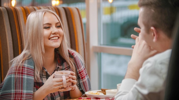 Una mujer bebe café y habla con su novio en el café.