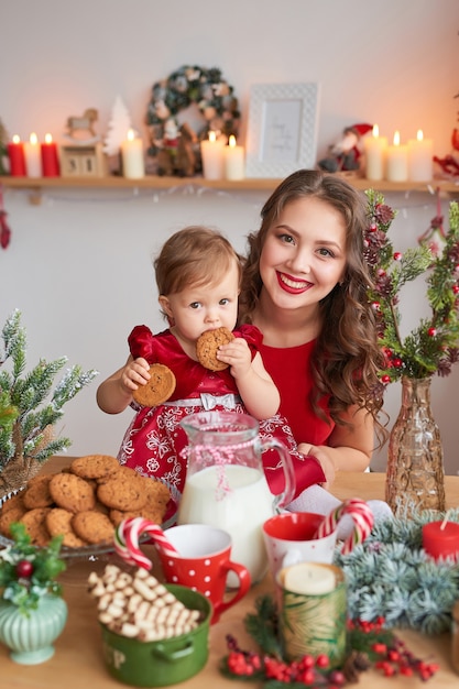 Mujer con bebé en la cocina decorada para Navidad.