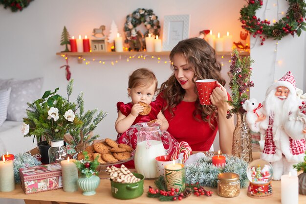 Mujer con bebé en la cocina decorada para Navidad.