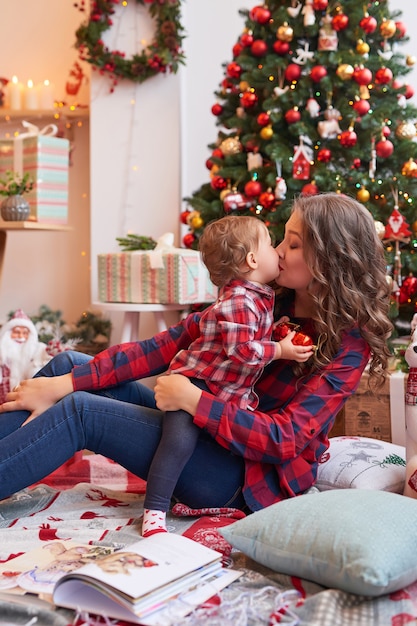 Mujer con bebé en la cocina decorada para Navidad.