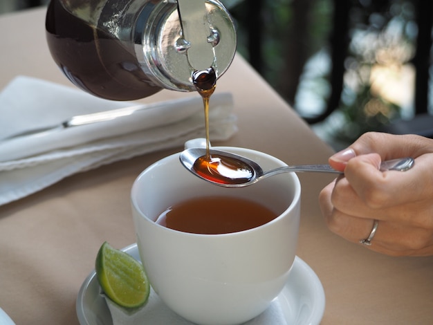 Mujer bebe té con miel en un restaurante