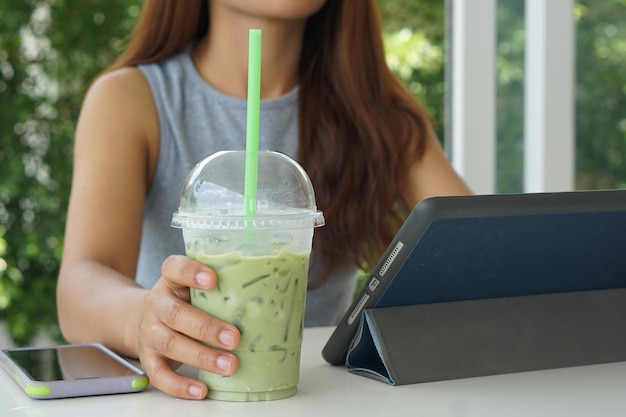 Una mujer bebe té verde de un vaso de plástico.