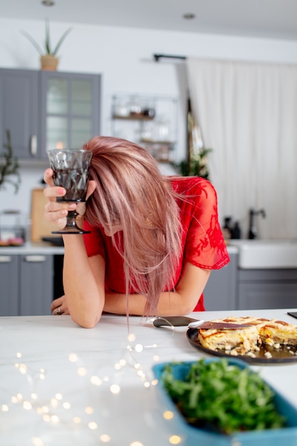 Mujer bebe un vino en la cocina después de una fiesta