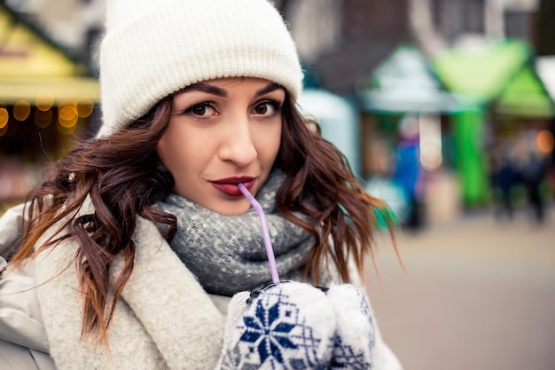 Mujer beber café caliente en la feria de invierno