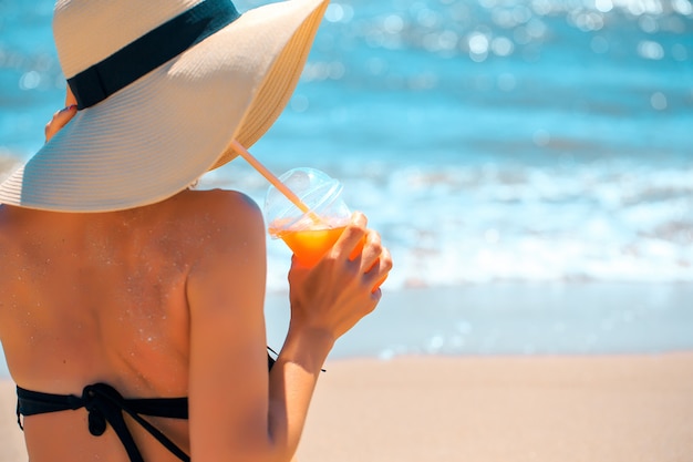 Mujer con bebida en el mar