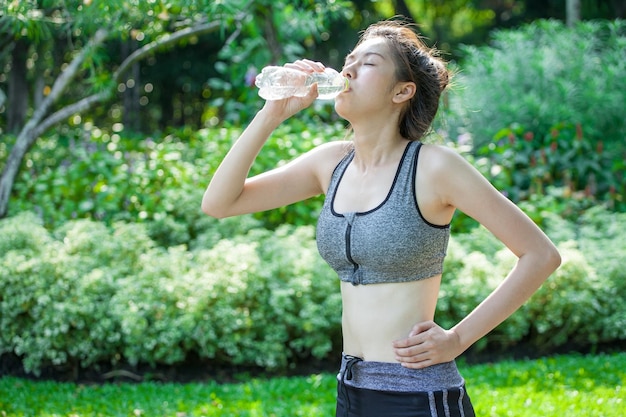 Mujer bebiendo agua de botella en el parque