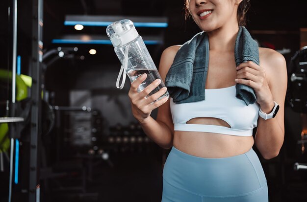 Mujer bebiendo agua recuperación salud ejercicio entrenamiento en gimnasio fitness descansar relajarse después del entrenamiento deporte con kettlebell pesas y botella de agua estilo de vida saludable culturismo