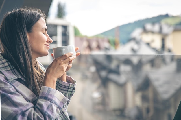 Una mujer bebiendo café en el balcón por la mañana.