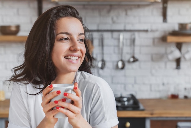Mujer bebiendo café por la mañana en la cocina de casa