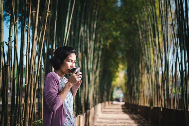 Foto mujer bebiendo café de pie en el parque