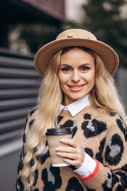 Mujer bebiendo café de una taza de cartón en la calle