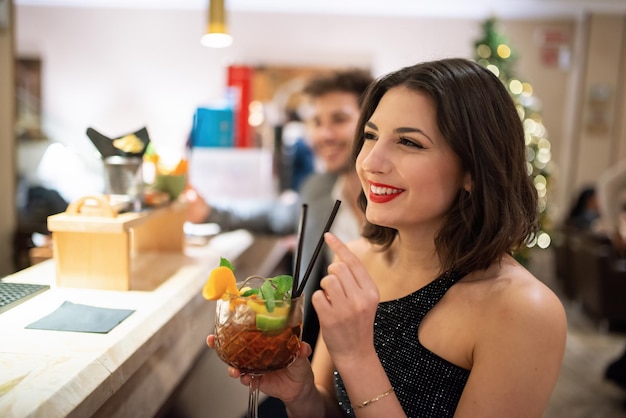 Foto mujer bebiendo un cóctel en un mostrador de bar