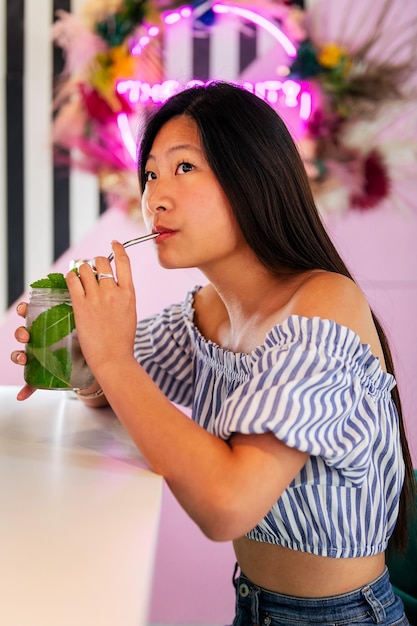 Mujer bebiendo un refresco en una cafetería de moda