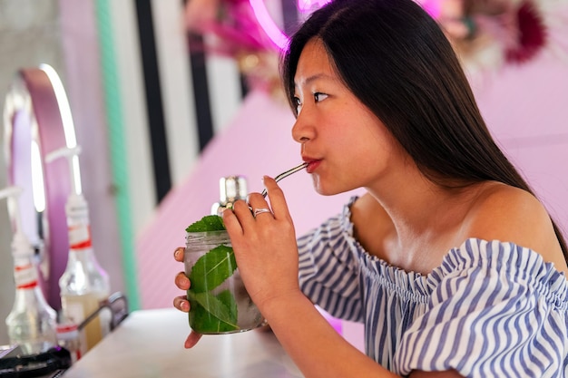 Mujer bebiendo un refresco en una cafetería de moda