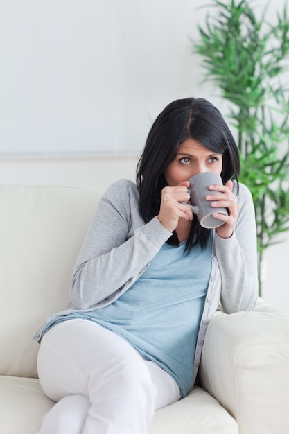 Mujer bebiendo de una taza gris