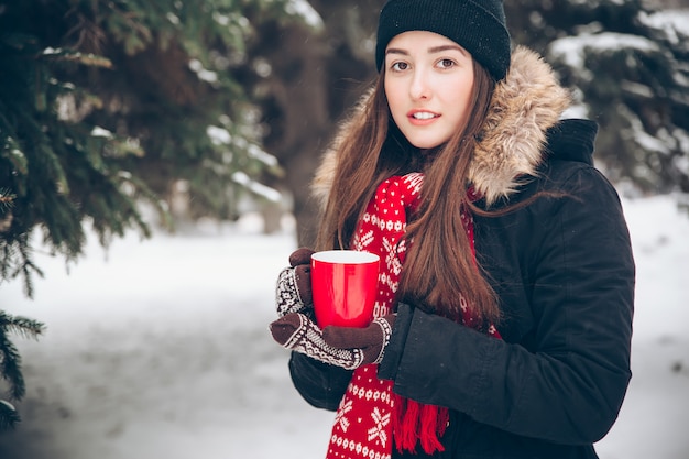 Mujer bebiendo té caliente en el bosque de invierno