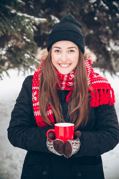 Mujer bebiendo té caliente en el bosque de invierno