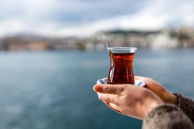 Mujer bebiendo té turco en la bahía del Bósforo en el fondo