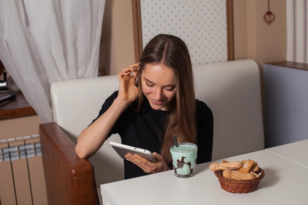 Mujer bebiendo té y usando tableta
