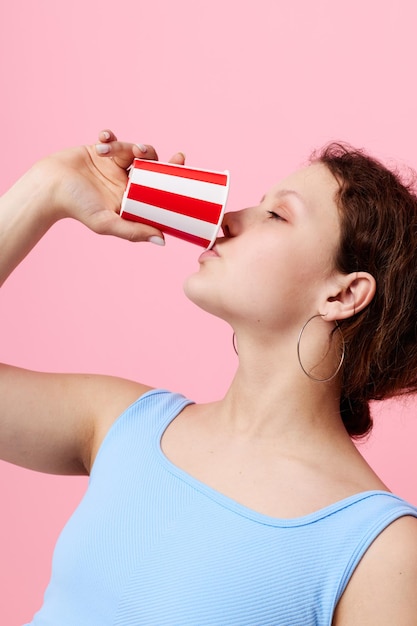 Mujer bebiendo de un vaso desechable closeup fondo rosa inalterado