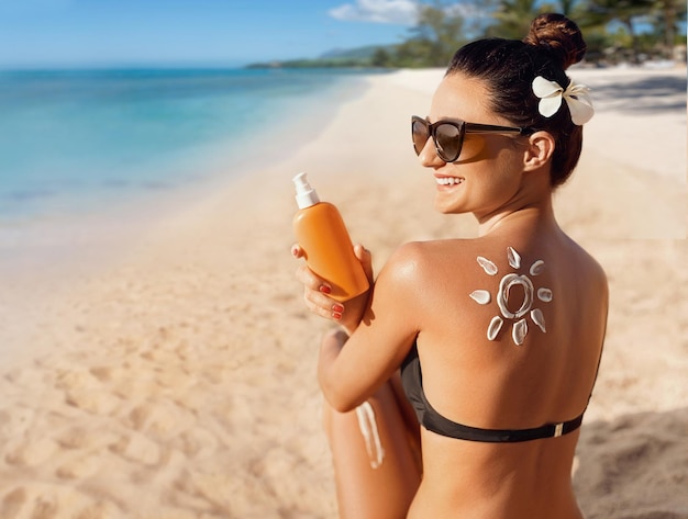 Mujer de belleza aplicando crema solar en el hombro bronceado en forma de protección solar solar