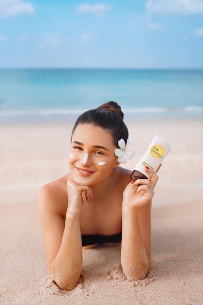 Mujer de belleza en Bikini sosteniendo botellas de protector solar en sus manos