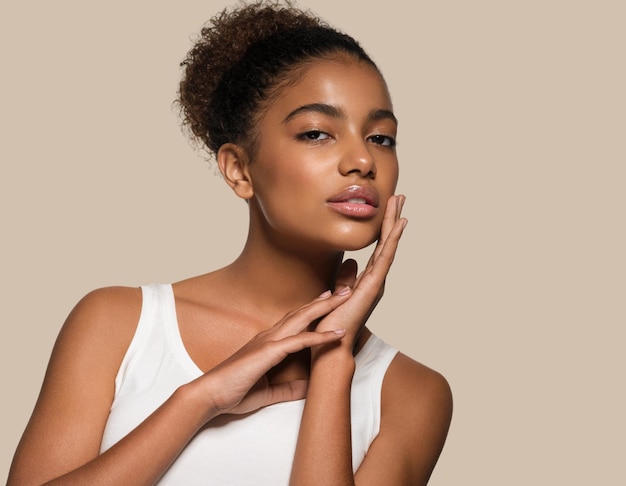 Mujer de belleza cara de piel negra modelo sonriente tocando su rostro. fondo de color marrón