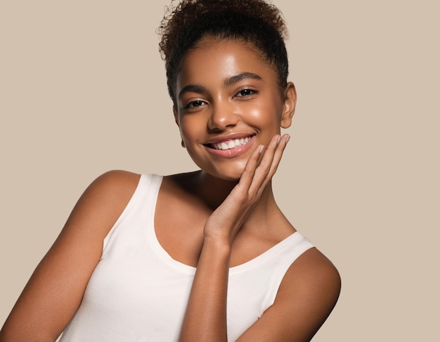 Mujer de belleza cara de piel negra modelo sonriente tocando su rostro. fondo de color marrón