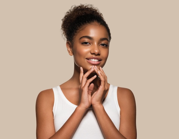 Mujer de belleza cara de piel negra modelo sonriente tocando su rostro. fondo de color marrón