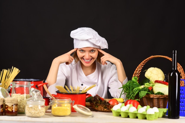 Mujer de belleza chef mujer chef con montón de verduras mujer atractiva alegre chef está sentado en