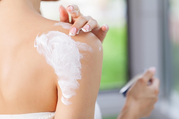 Mujer de belleza con concepto de crema hidratante en el baño.