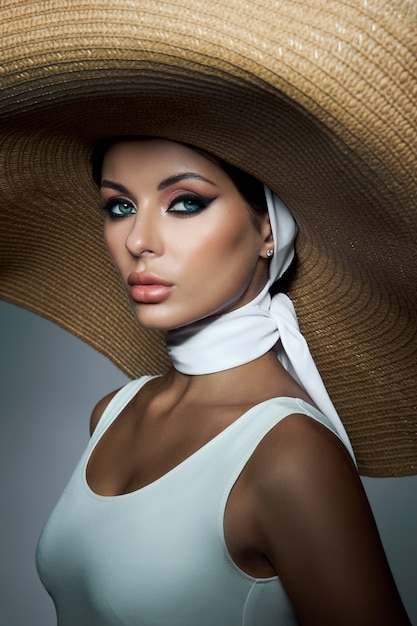 Mujer de belleza con un gran sombrero de mimbre y un vestido ligero de verano. Maquillaje ahumado, retrato perfecto de una mujer