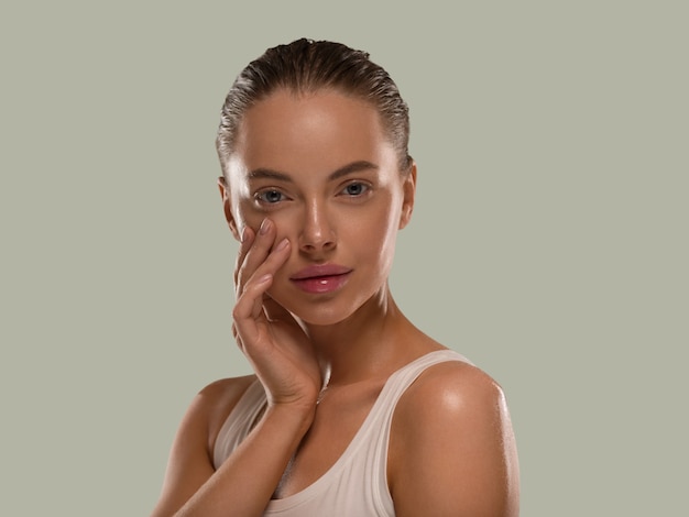 Mujer de belleza con manos naturales sanas componen la piel limpia y fresca concepto color de fondo verde