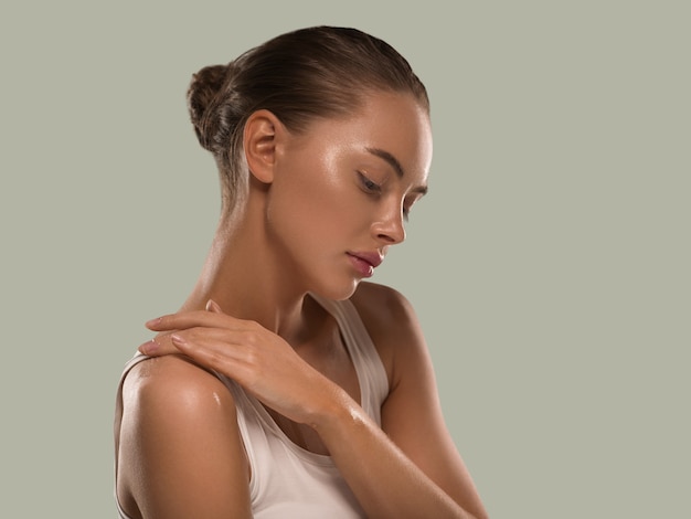 Mujer de belleza con manos naturales sanas componen la piel limpia y fresca concepto color de fondo verde