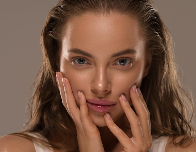 Mujer de belleza con manos saludable maquillaje natural concepto de piel limpia y fresca fondo de color