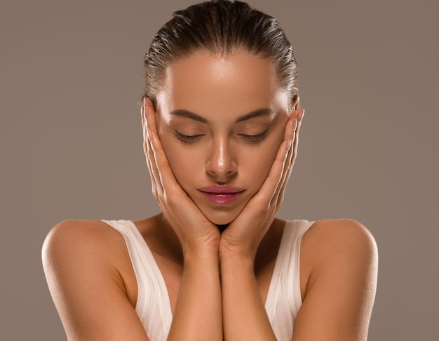 Mujer de belleza con manos saludable maquillaje natural concepto de piel limpia y fresca fondo de color