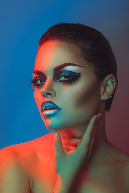 Mujer de belleza con maquillaje y piel sana en luces rojas y azules en estudio