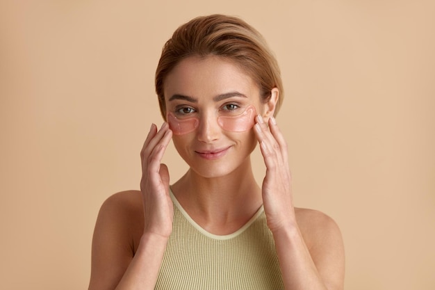 Mujer de belleza de piel de ojos posando con parches de ojos de hidrogel de colágeno debajo de los ojos