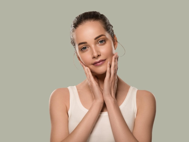 Mujer de belleza piel sana tocando su rostro. Hermosa mujer. Fondo de color. Verde