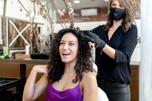 Mujer de belleza sentada en un salón de peluquería mientras es atendida