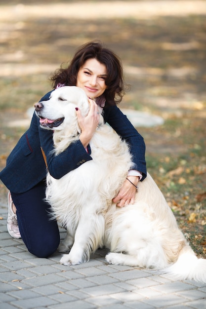 Mujer de belleza con su perro jugando al aire libre. Mujer caminando Labrador Retriever en el parque.