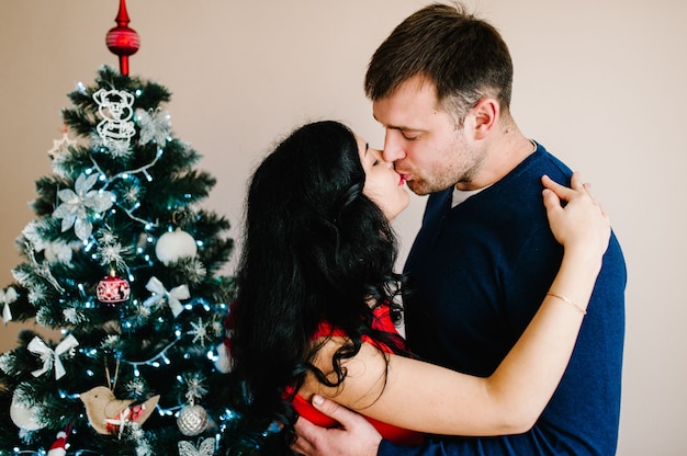 Mujer besa al hombre cerca del árbol. Feliz Navidad. ¡Felices vacaciones! Concepto de amor. Disfrutando juntos.