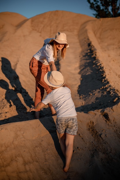 Mujer besada por su amado hijo durante la puesta de sol. Madre con su hijo en una duna de arena. Viaje.
