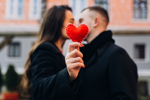 Mujer besando a hombre mientras muestra corazón rojo